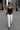 Woman walking on a city street wearing a black top and white pants.