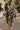 Woman wearing a long sleeve noir palm skirt set walking on through resort.